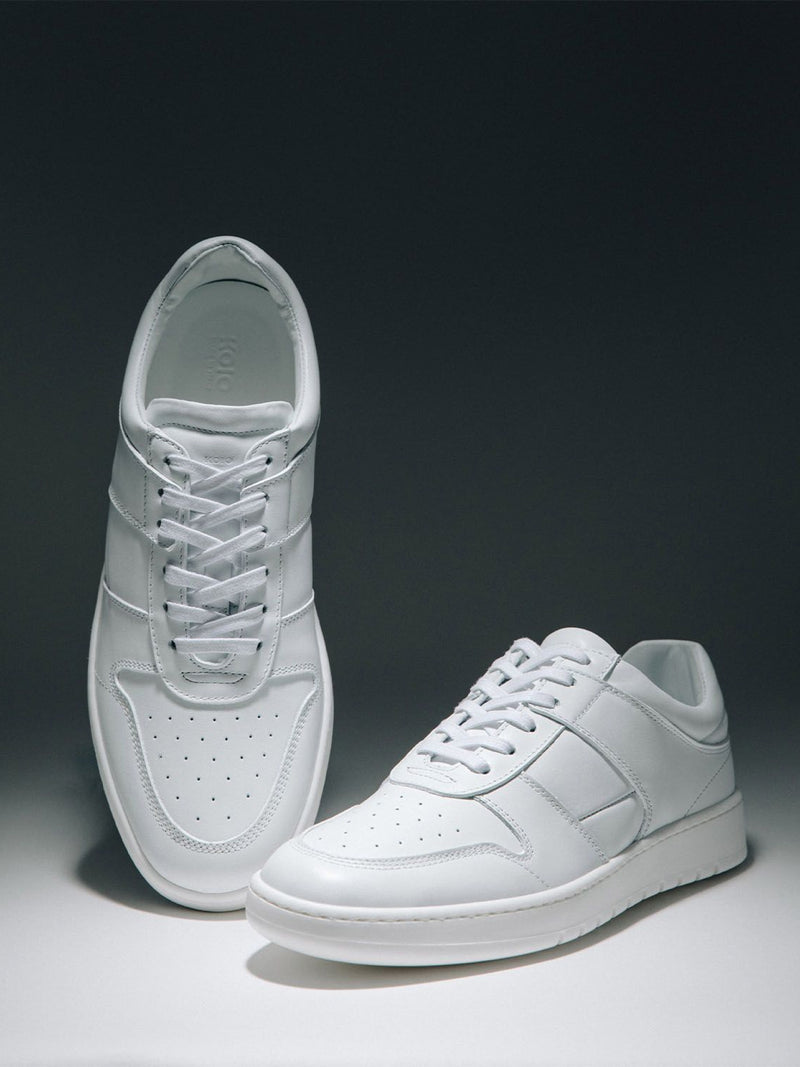 Top and side views of white low-top sneakers showcasing perforated toe boxes with a dark gray background