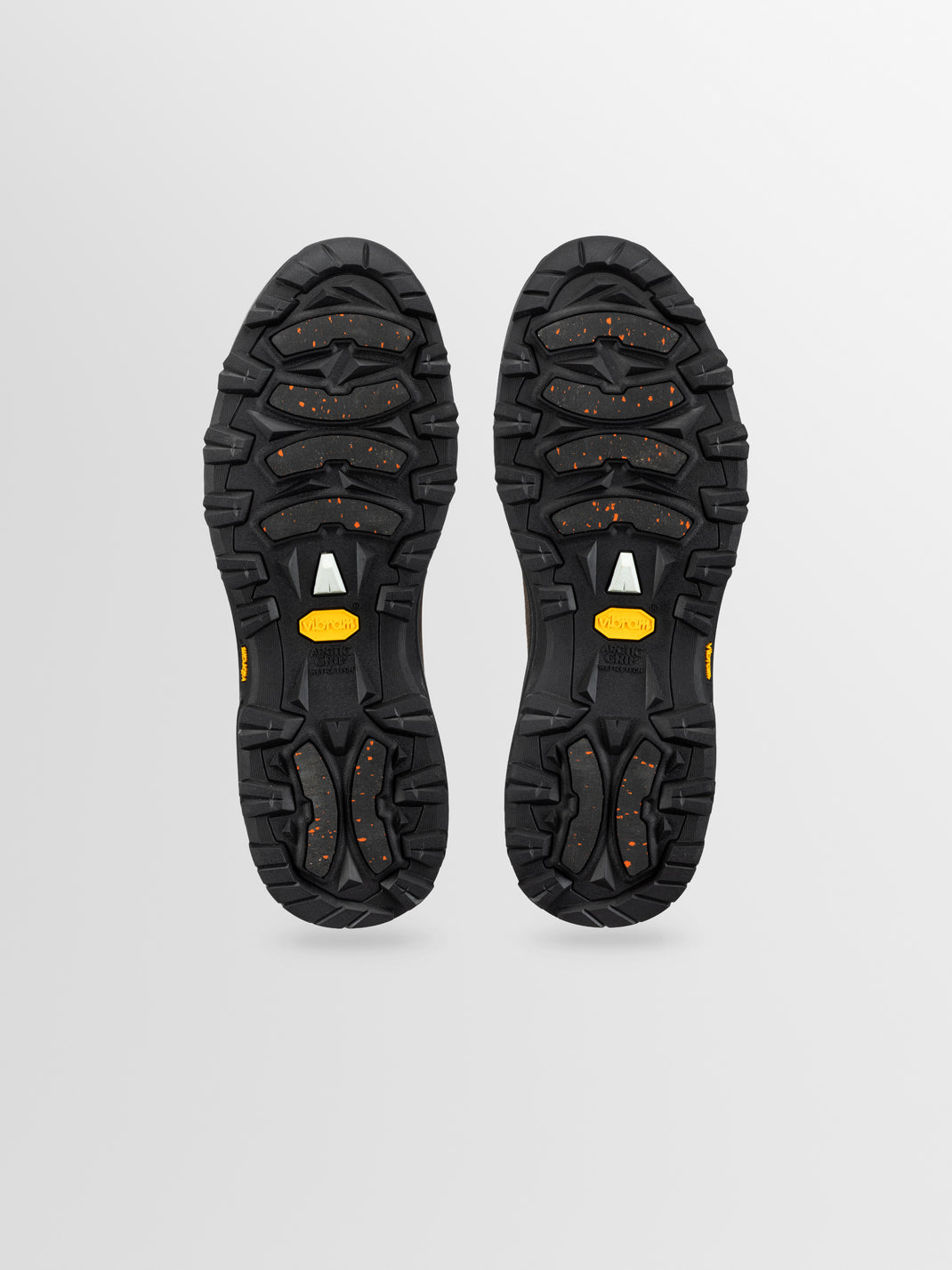 Bottom of boot soles in black rubber with red dot accents and yellow brand label.
