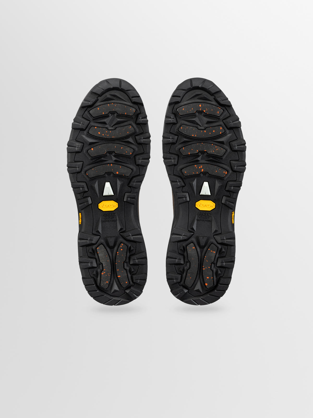 Bottom of boot soles in black rubber with red dot accents and yellow brand label.