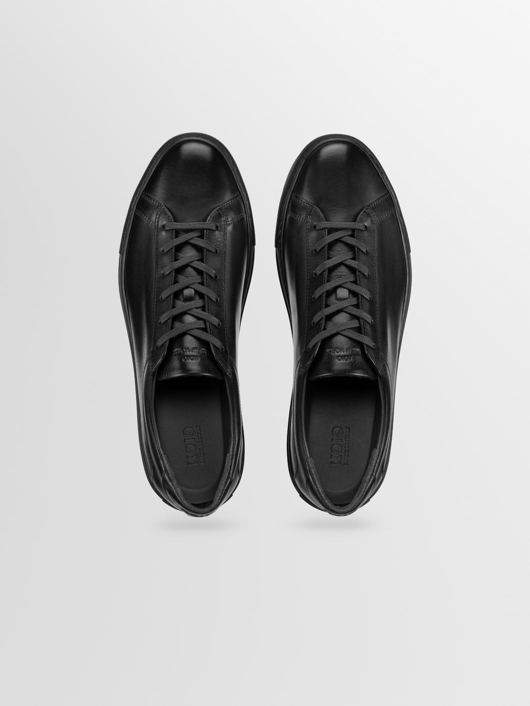 Top view of Capri in Antica Nero low-top sneakers showcasing black leather uppers and laces on a light gray background