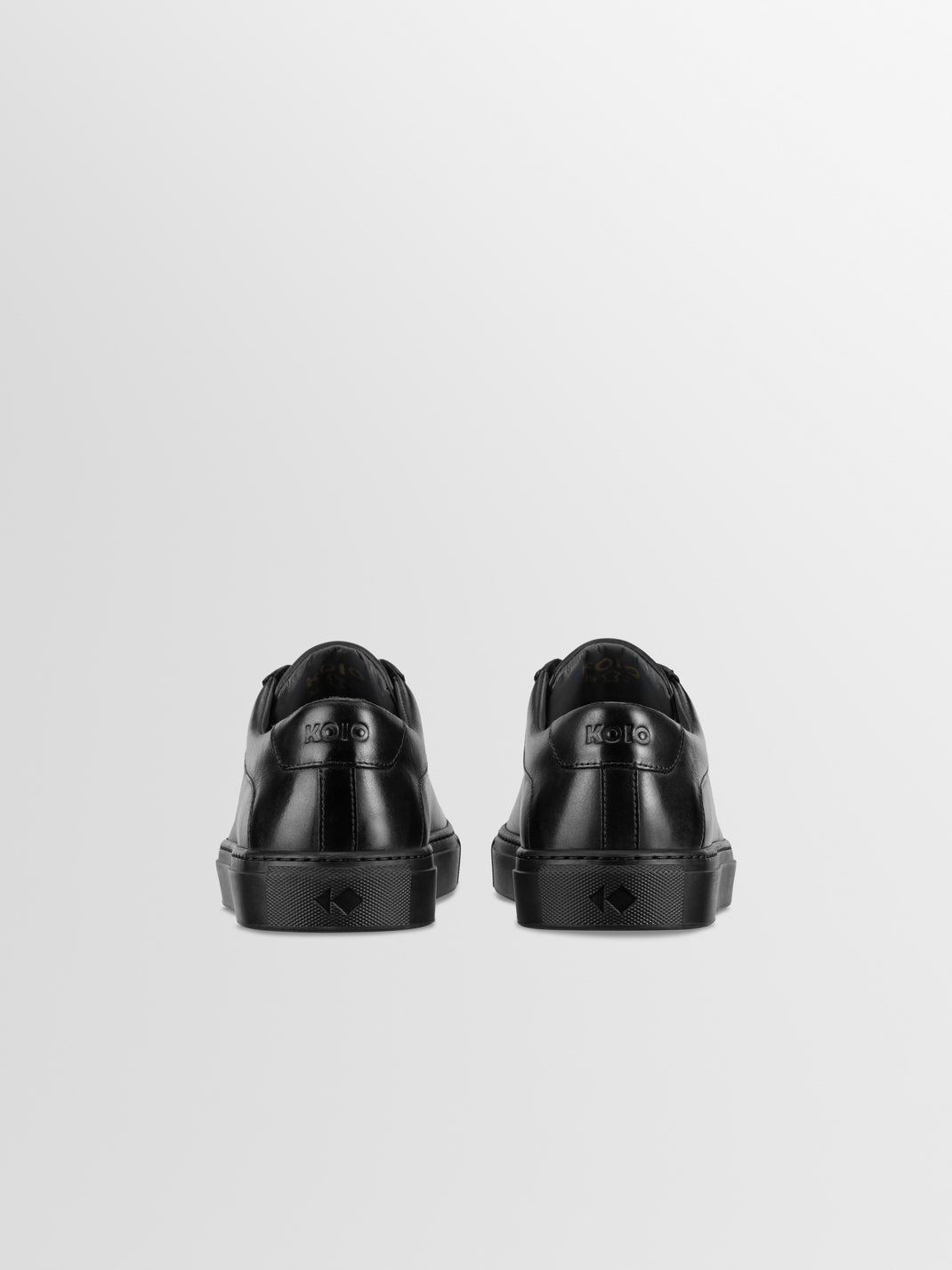 Rear view of Capri in Antica Nero low-top sneakers showcasing black leather uppers and branded heels against a light gray background