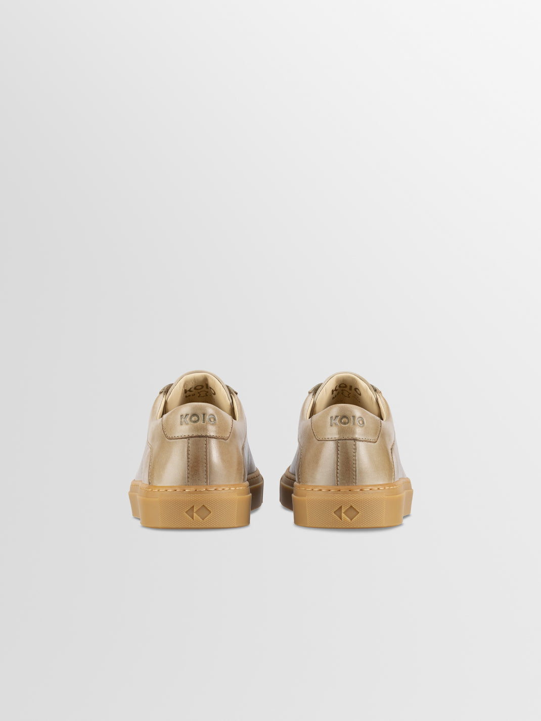 Rear view of men’s Capri in Antica Perla low-top sneakers showcasing KOIO heel branding and gum rubber soles on a light gray background