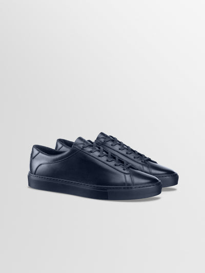 Three-quarter view of Capri in Antica Space men’s navy leather low-top sneakers showcasing lace-up design on a light gray background