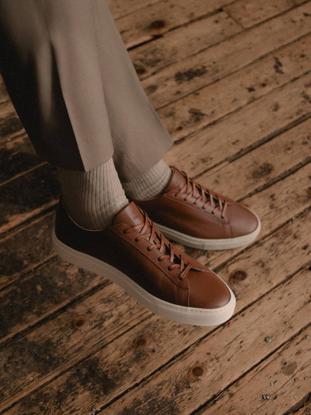 Angled view of Capri in Terra low-top sneakers showcasing brown leather uppers and white rubber soles on a wood floor