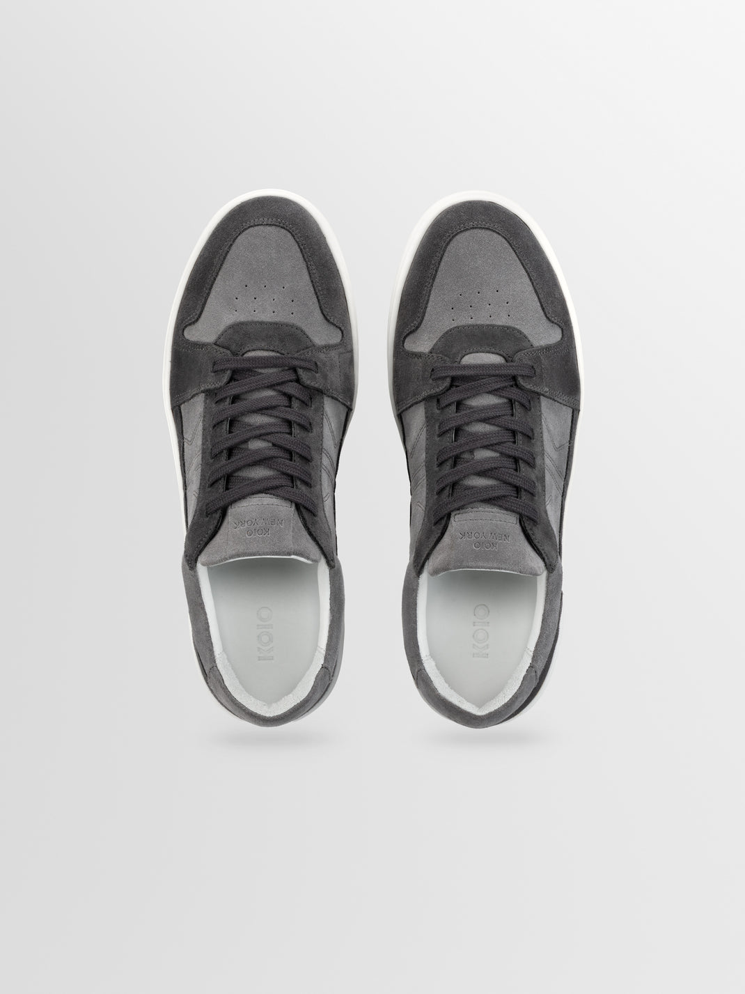 Top view of Carrara ash gray suede low-top sneakers showcasing lace-up uppers and white rubber soles with a light gray background
