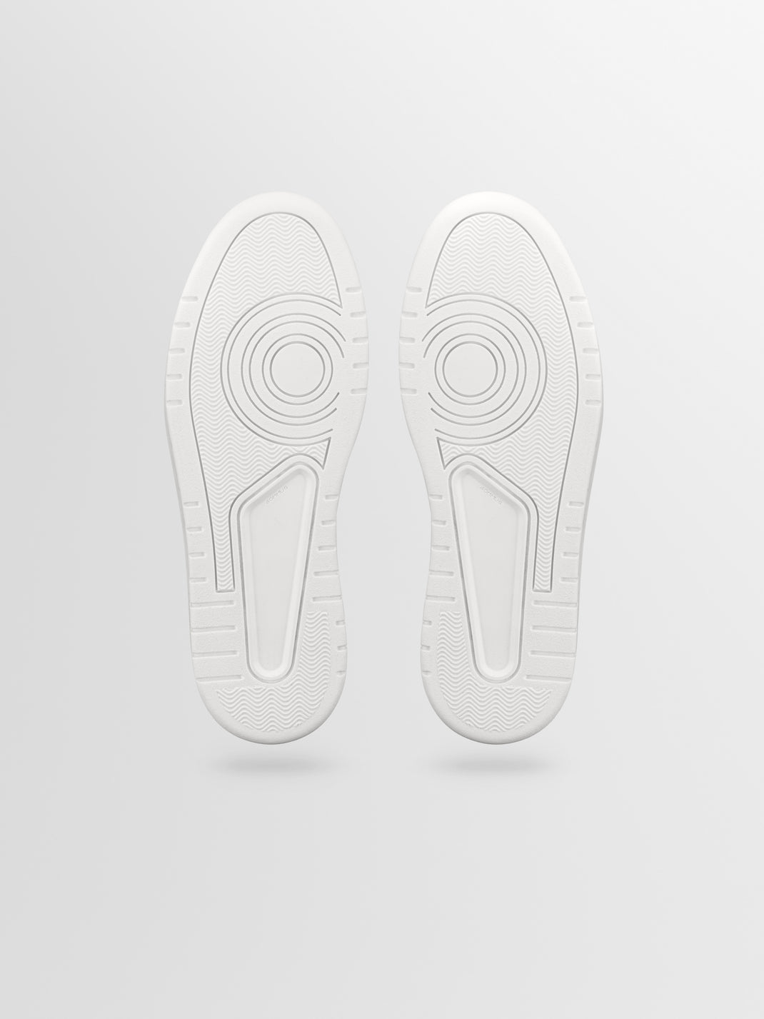 Bottom view of Carrara ash gray men’s suede sneakers showcasing textured rubber soles on a light gray background