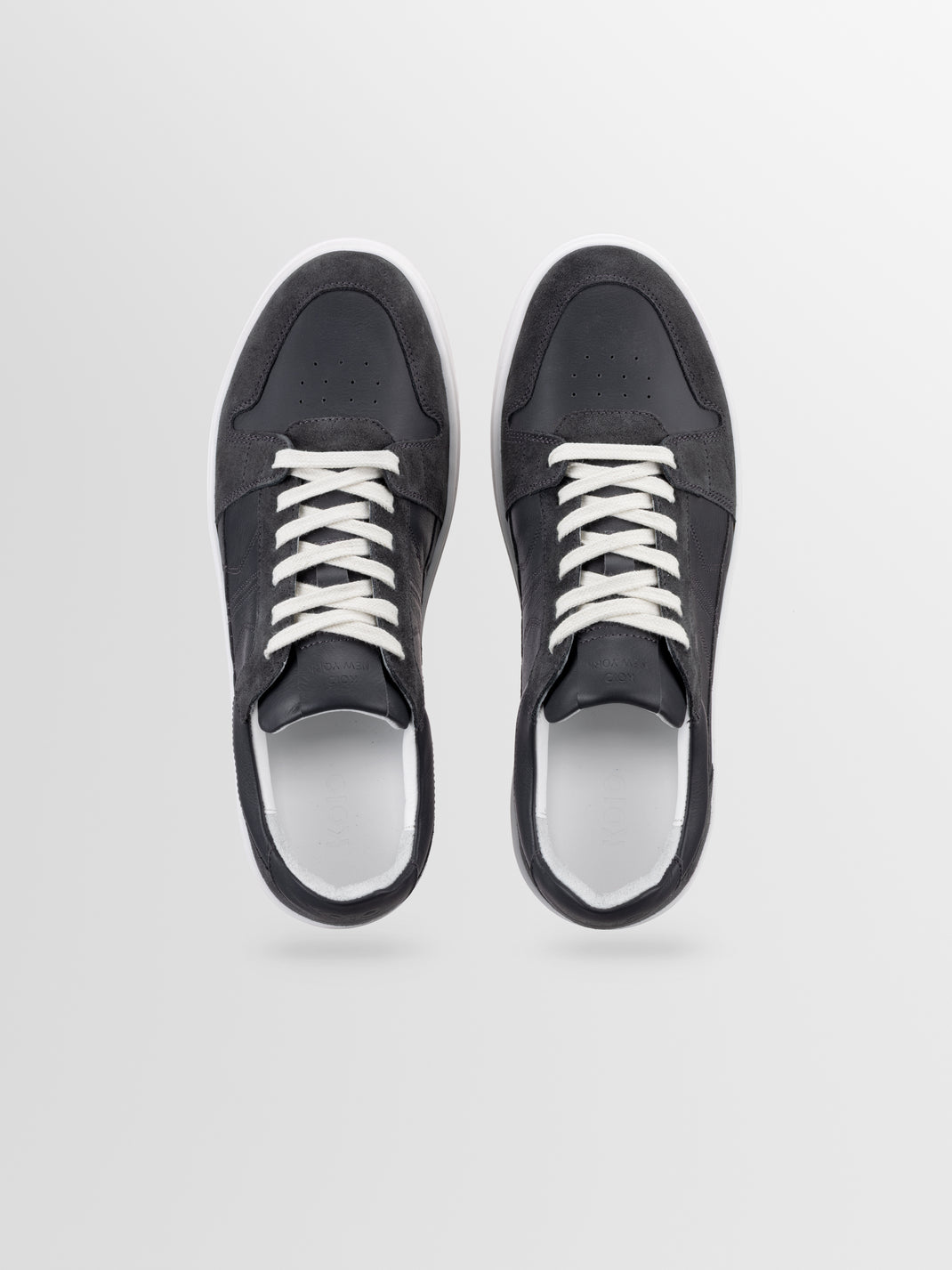 Top view of men’s black suede Carrara low-top sneakers showcasing white laces and white soles on a light gray background