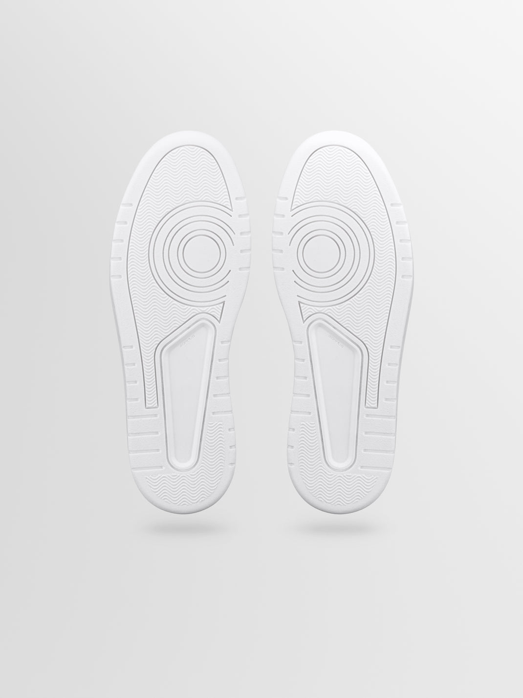 Bottom view of Carrara in Basalt men’s black suede sneakers showcasing white rubber soles with patterned tread on a light gray background