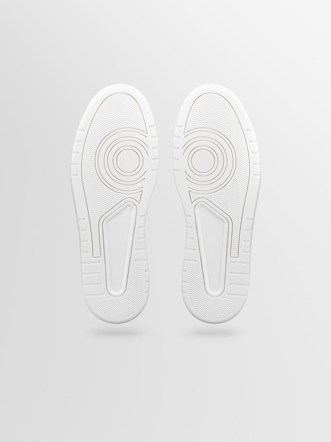 Bottom view of Carrara suede sneaker showcasing textured white outsoles with a light gray background