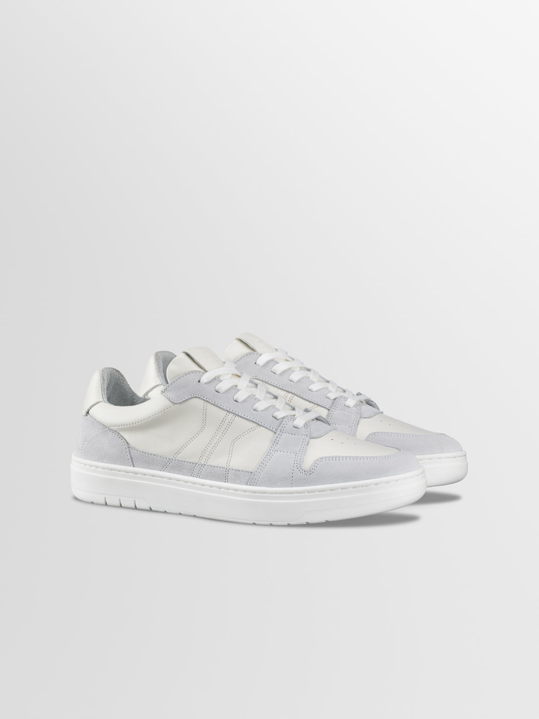 Three-quarter view of Carrara in Ice low-top sneakers showcasing white and grey suede panels on a light gray background