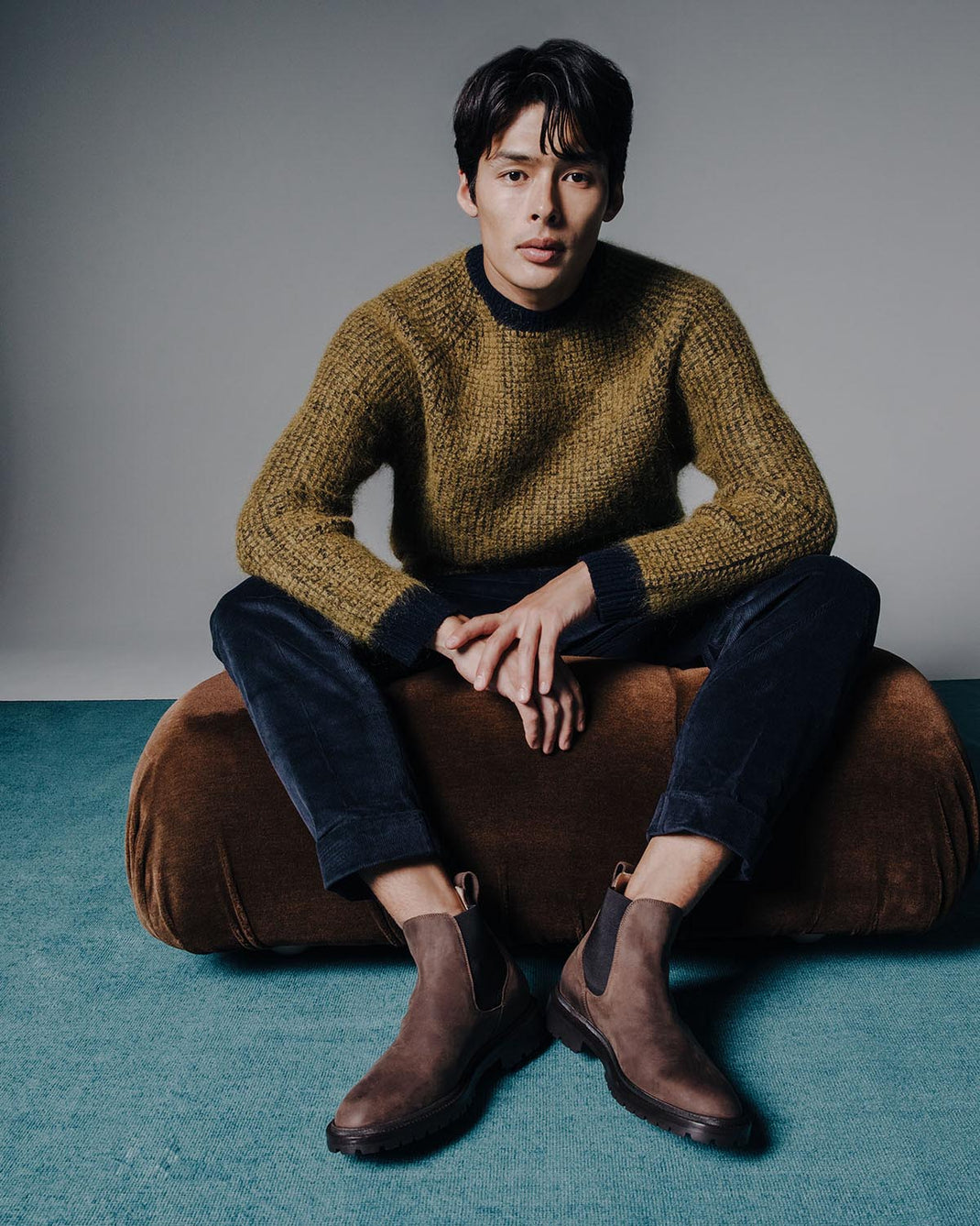 Front view of Fermo chocolate nubuck Chelsea boots showcasing elastic side panels and lug soles on a seated model in a studio