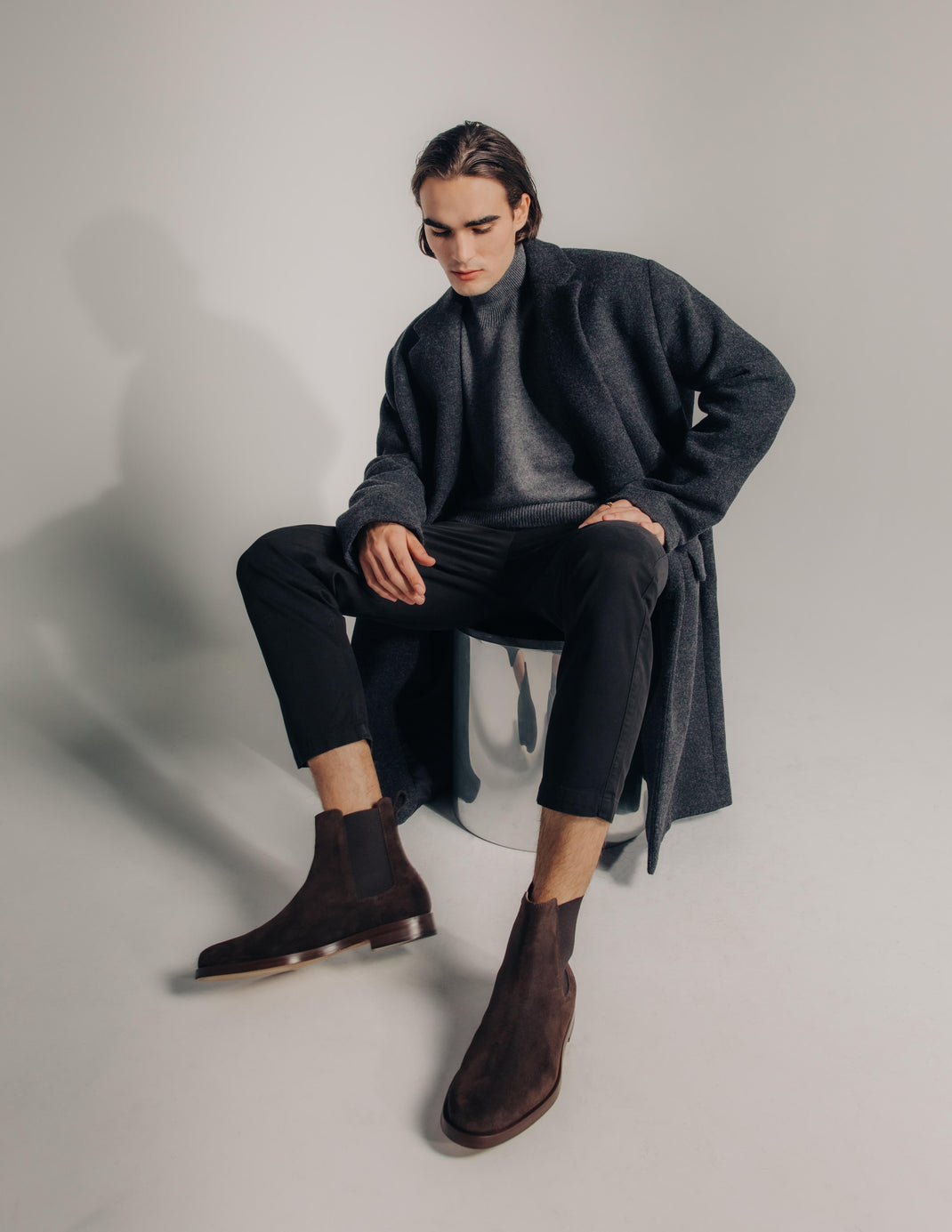 Three-quarter view of Trento dark brown suede boots in Root showcasing elastic side panels worn by a seated model