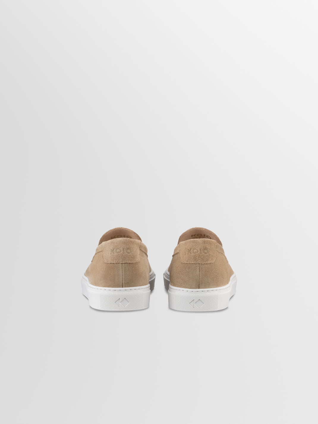 Rear view of men’s beige suede slip-on loafer in Fawn showcasing white soles against a light gray background