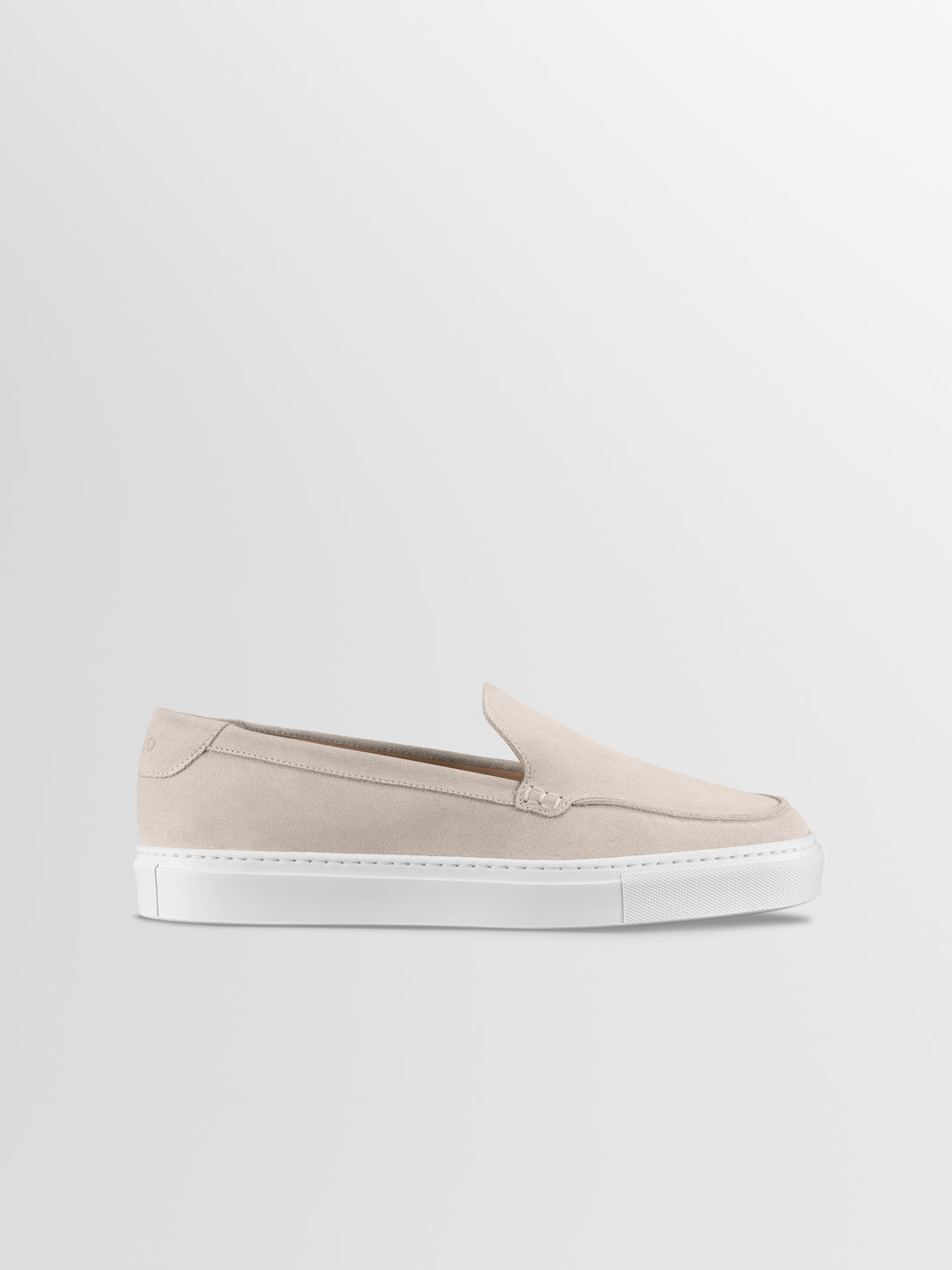 Side view of the Lido in Ivory men’s beige suede slip-on loafer showcasing its white rubber sole on a light gray background