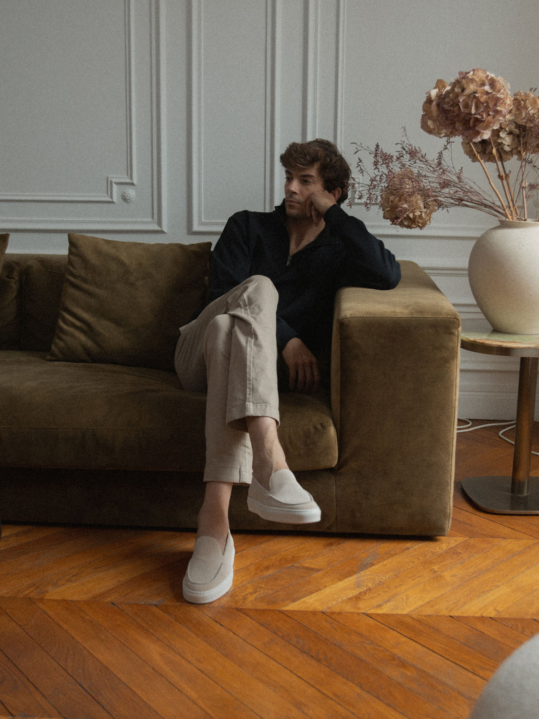 Man sitting on a sofa wearing the Lido ivory suede slip-on loafers