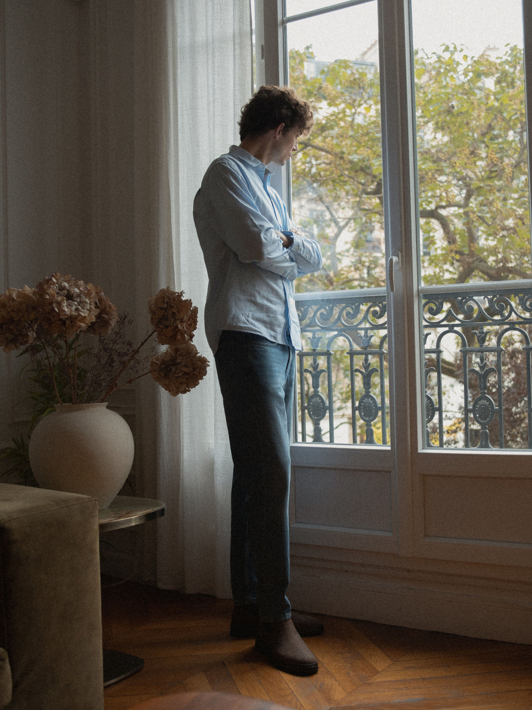 Man wearing a chocolate nubuck Chelsea boot standing by a window