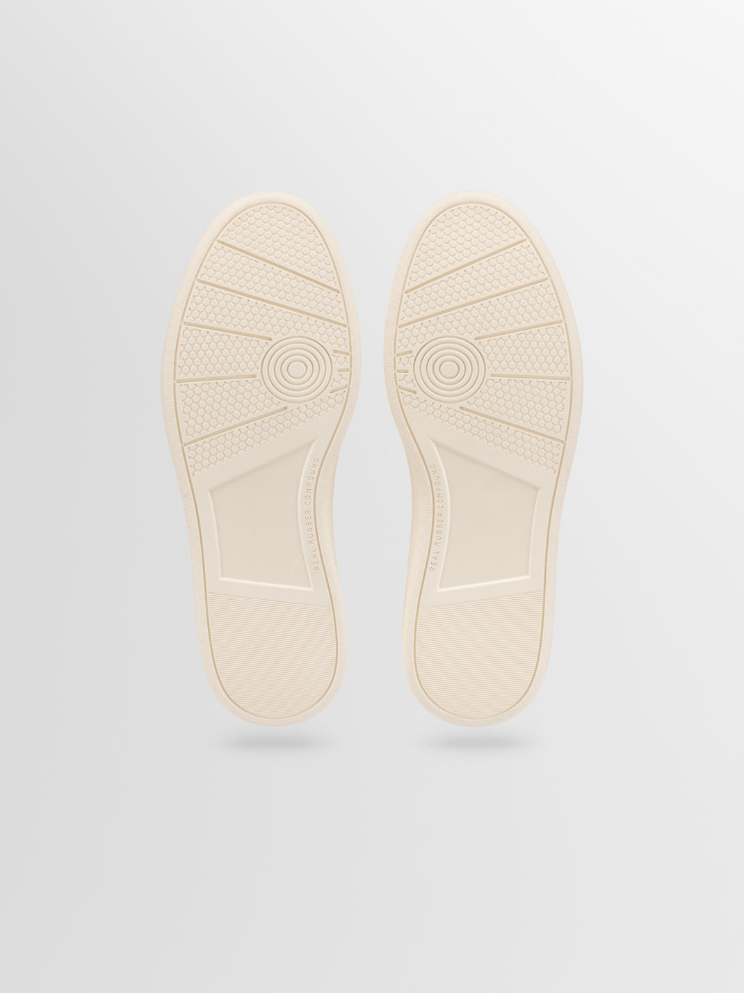 Bottom view of Monza low-top sneakers in Birch showcasing textured rubber soles against a light gray background