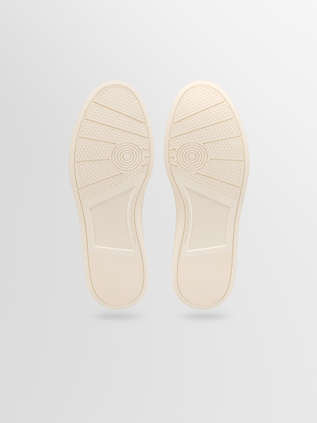 Bottom view of the Monza men’s low-top sneaker showcasing cream patterned rubber soles with a light gray background