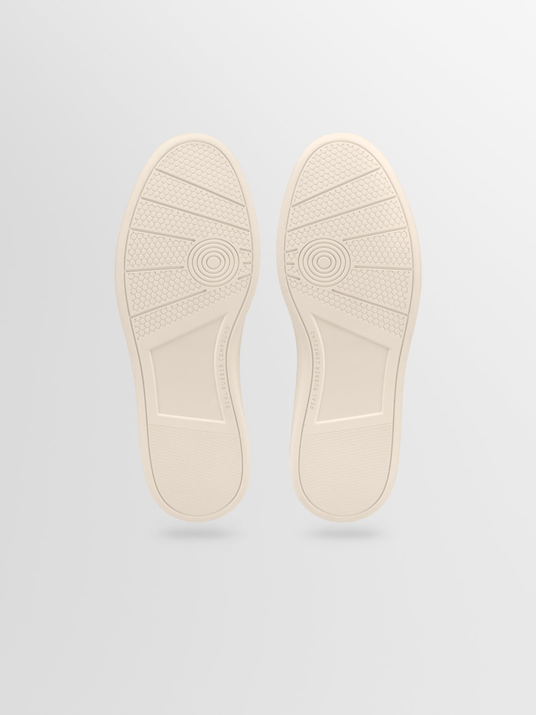 Bottom view of Monza in Wheat low top sneakers showcasing beige rubber soles with patterned tread on a light gray background