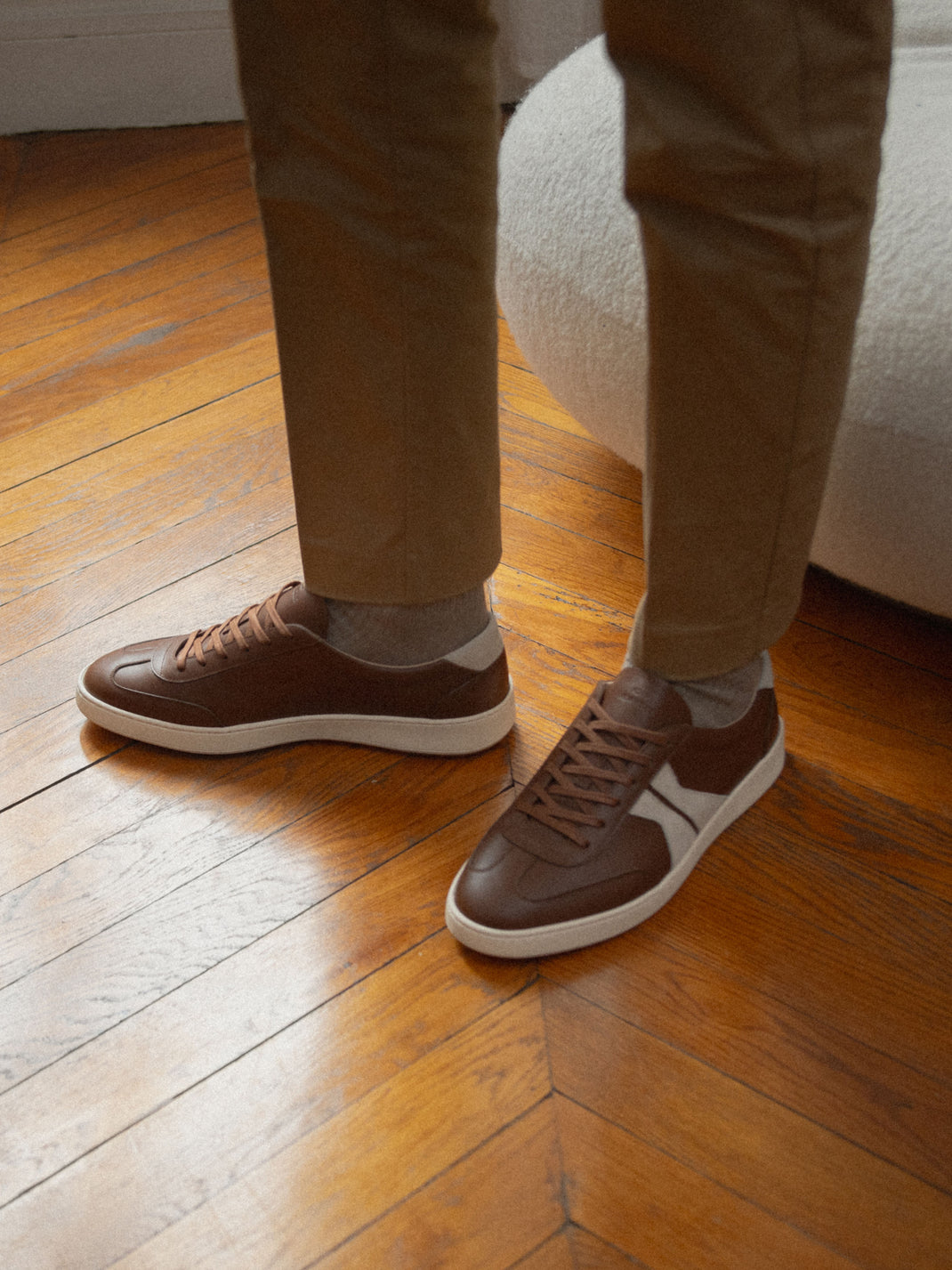 Side view of Monza in Tobacco low-top sneakers showcasing brown leather uppers and white soles on a model indoors