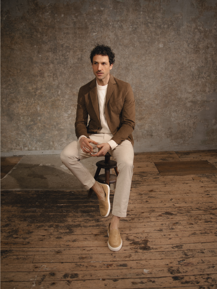 Man sitting wearing men's Italian light brown leather loafer sneakers with white rubber soles