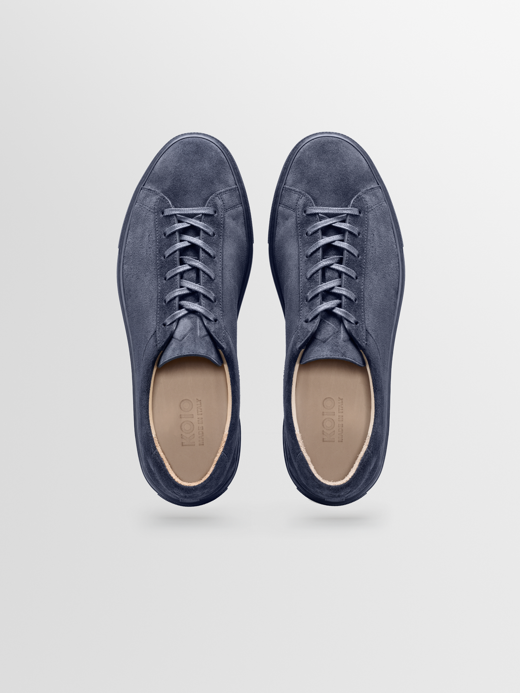 Top view of Capri men’s navy suede low-top sneakers showcasing laces and tan insoles on a light gray background
