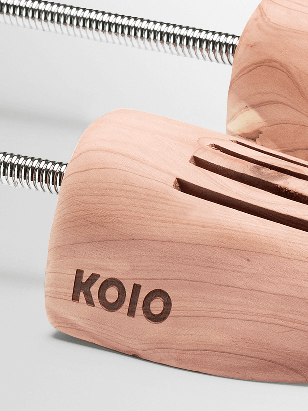 Close-up of KOIO shoe tree showcasing its wooden body and coiled metal spring against a light background